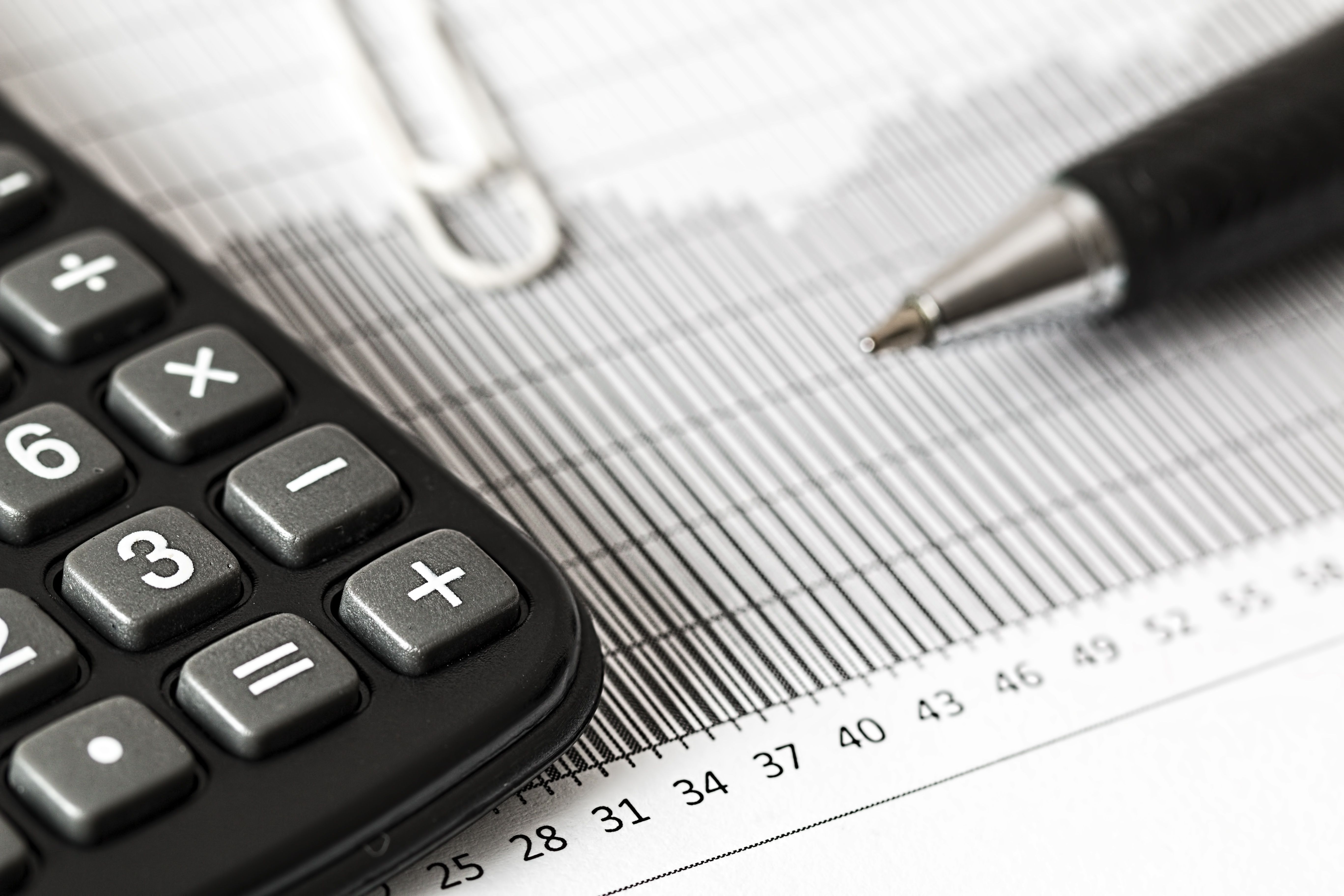 Calculator and pen on a bar chart representing financial analysis of business expenses