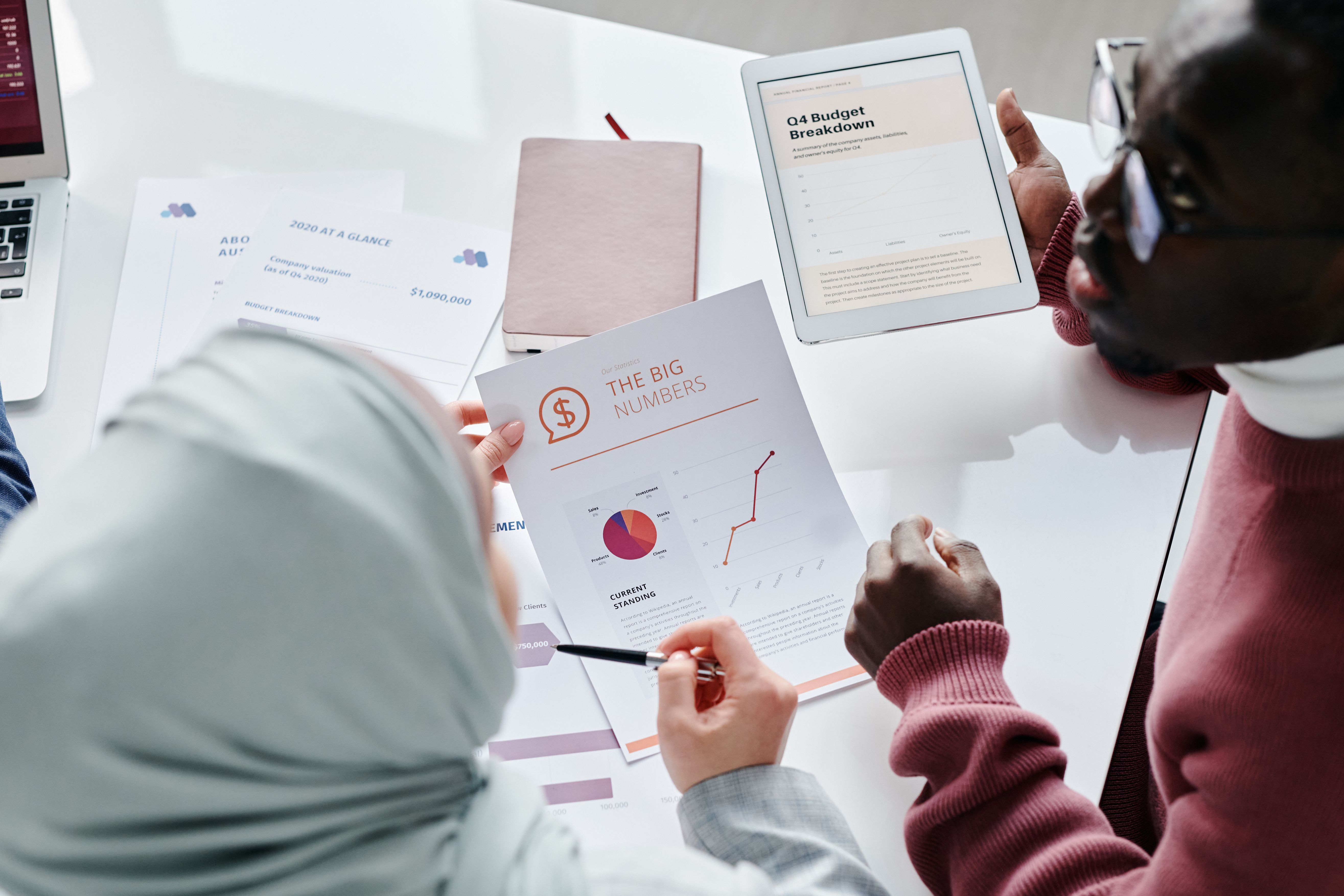 Two colleagues reviewing financial documents and graphs in an office meeting