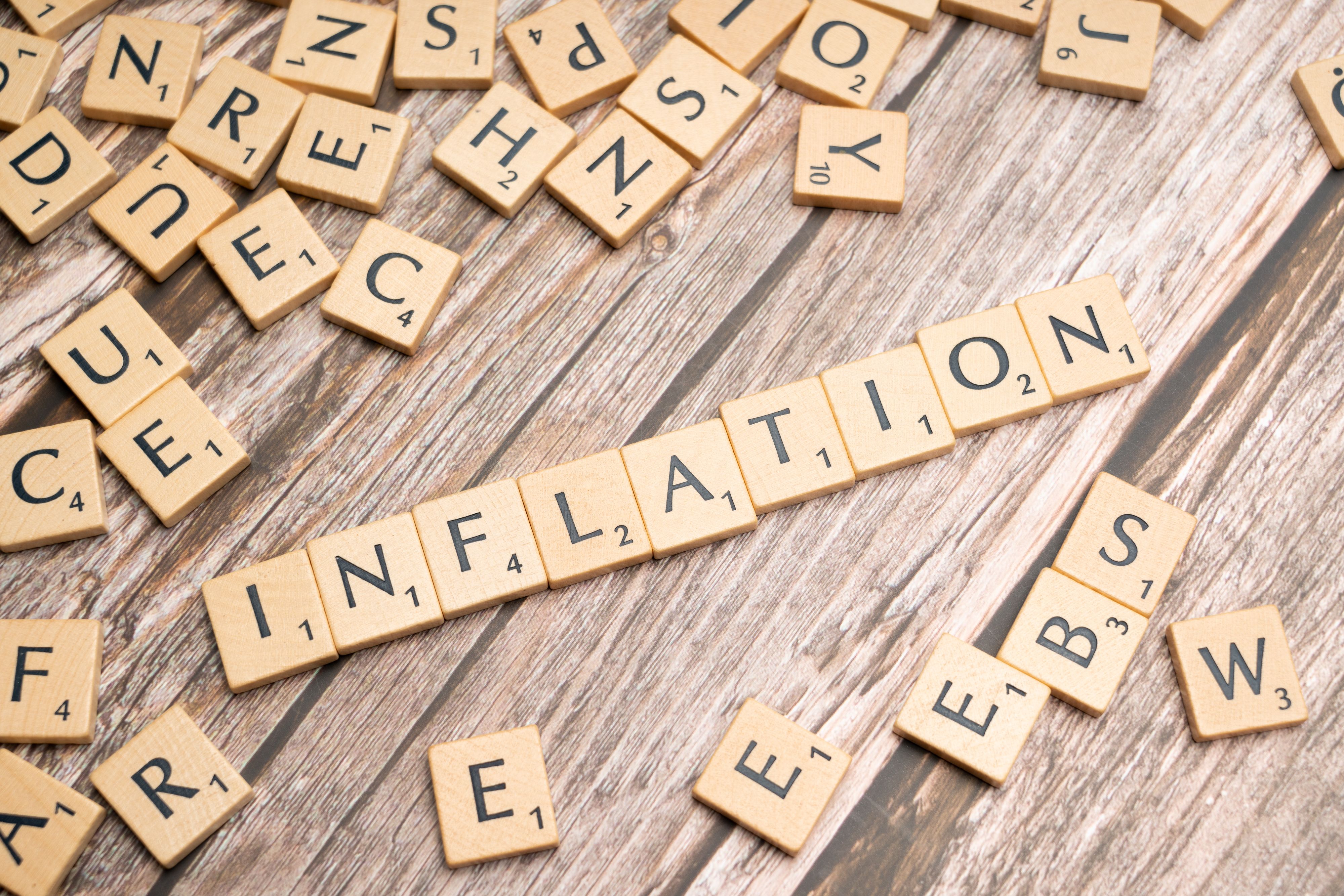 Wooden letter tiles spelling the word inflation on a rustic table, symbolizing economic pressure on voters.