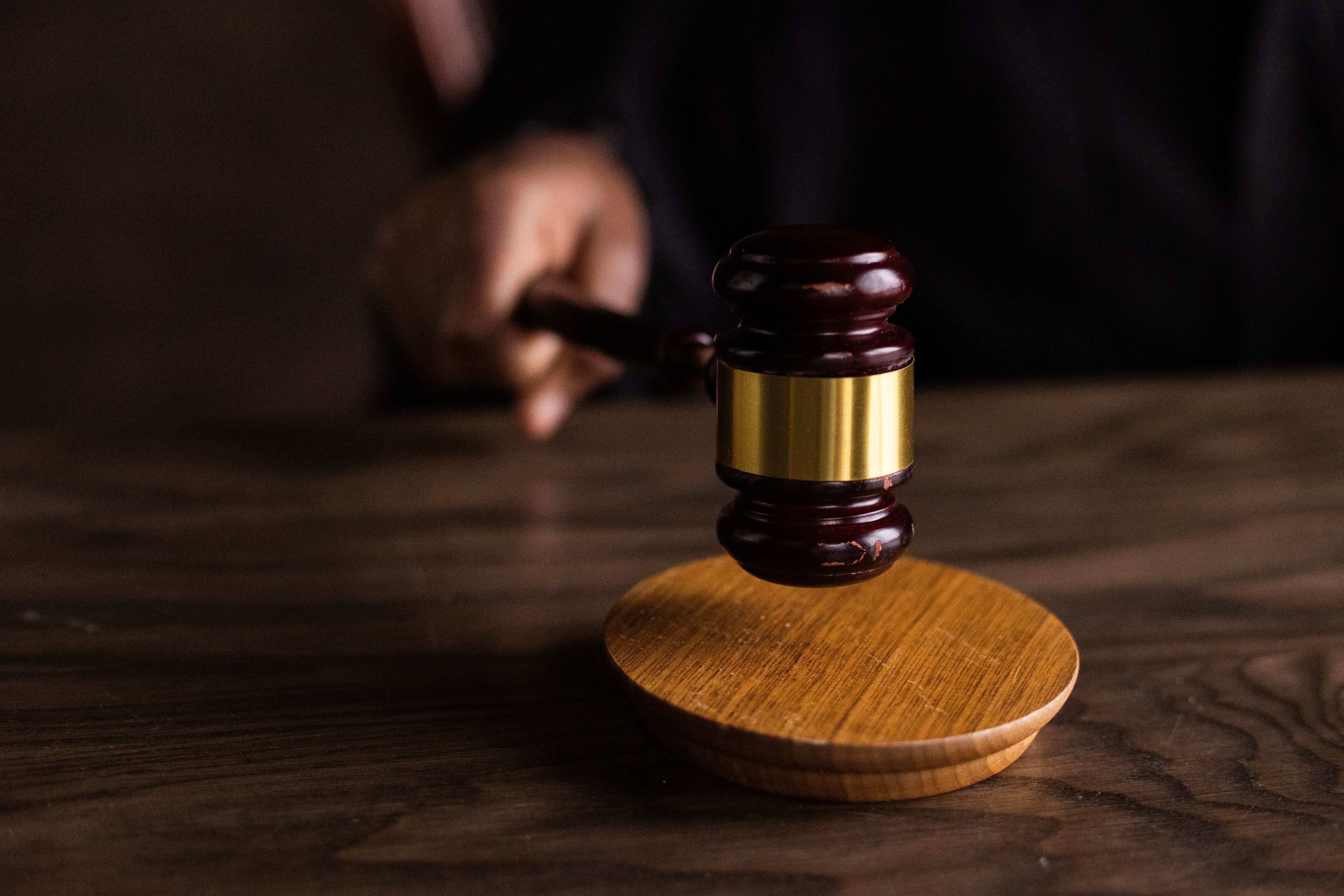 Wooden gavel striking a sound block in a courtroom representing litigation