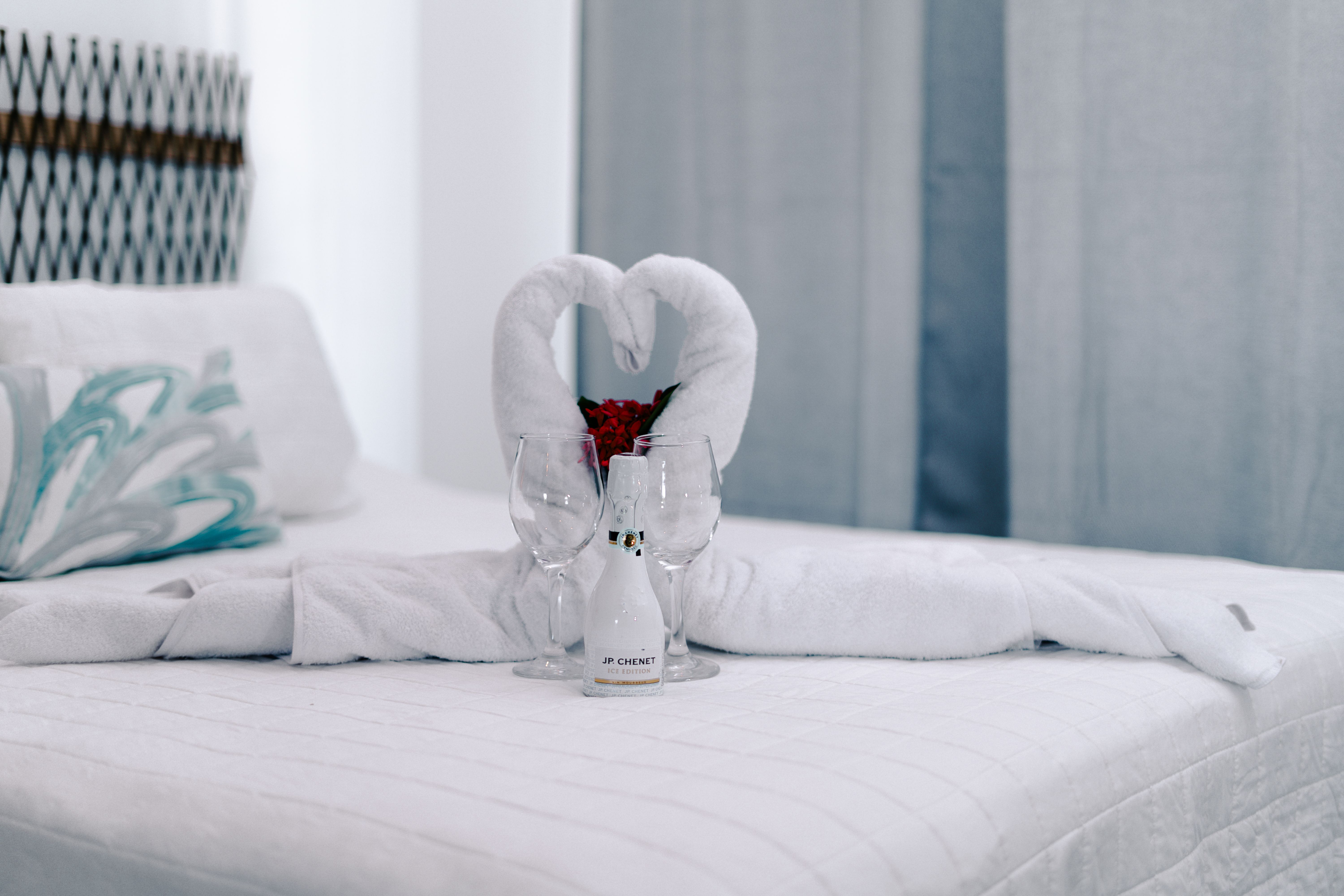 Romantic hotel room arrangement with towel swans and wine, a polished personal touch for a special occasion.