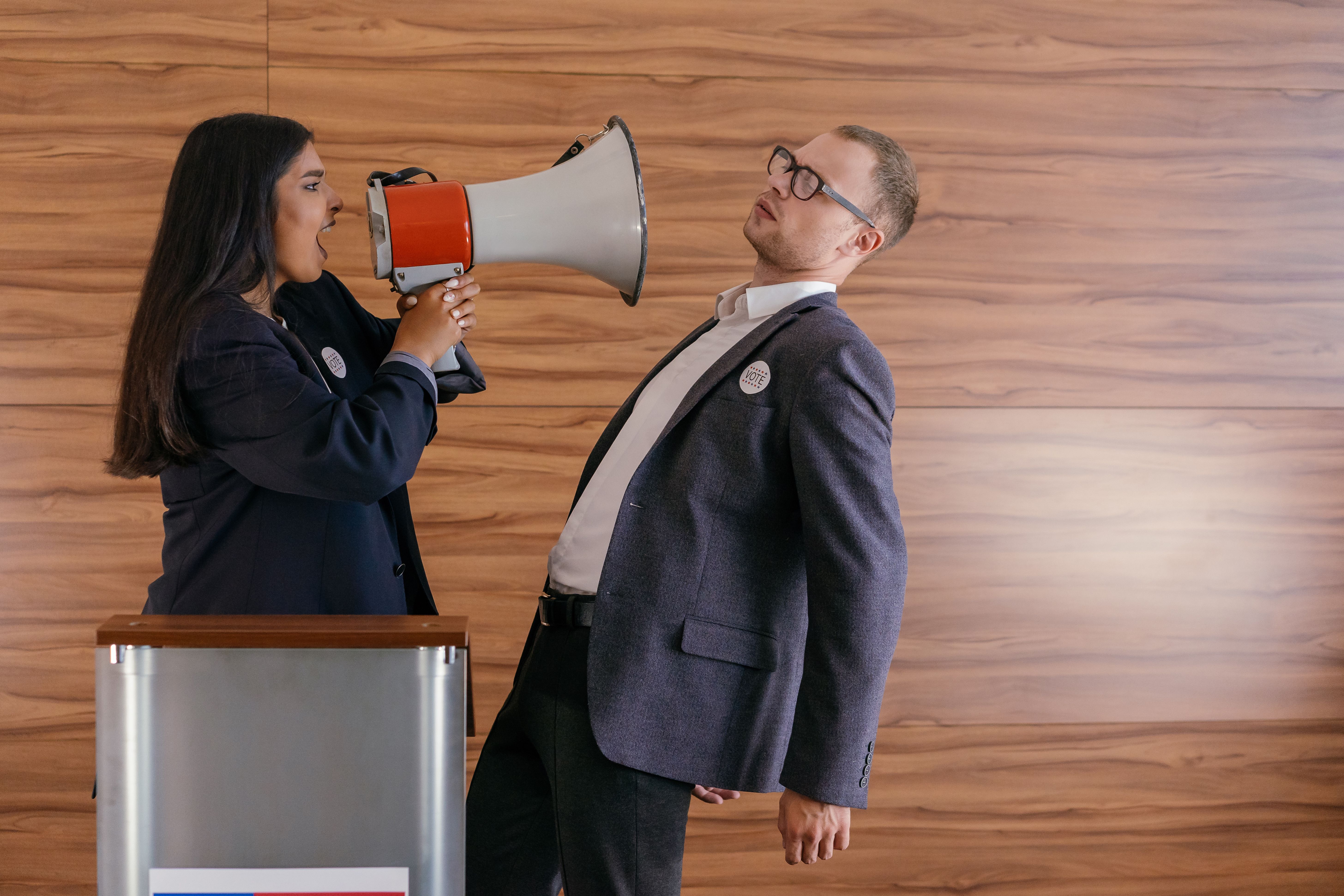 Two politicians in a heated debate, one shouting into a megaphone, illustrating campaign messages on economic issues.