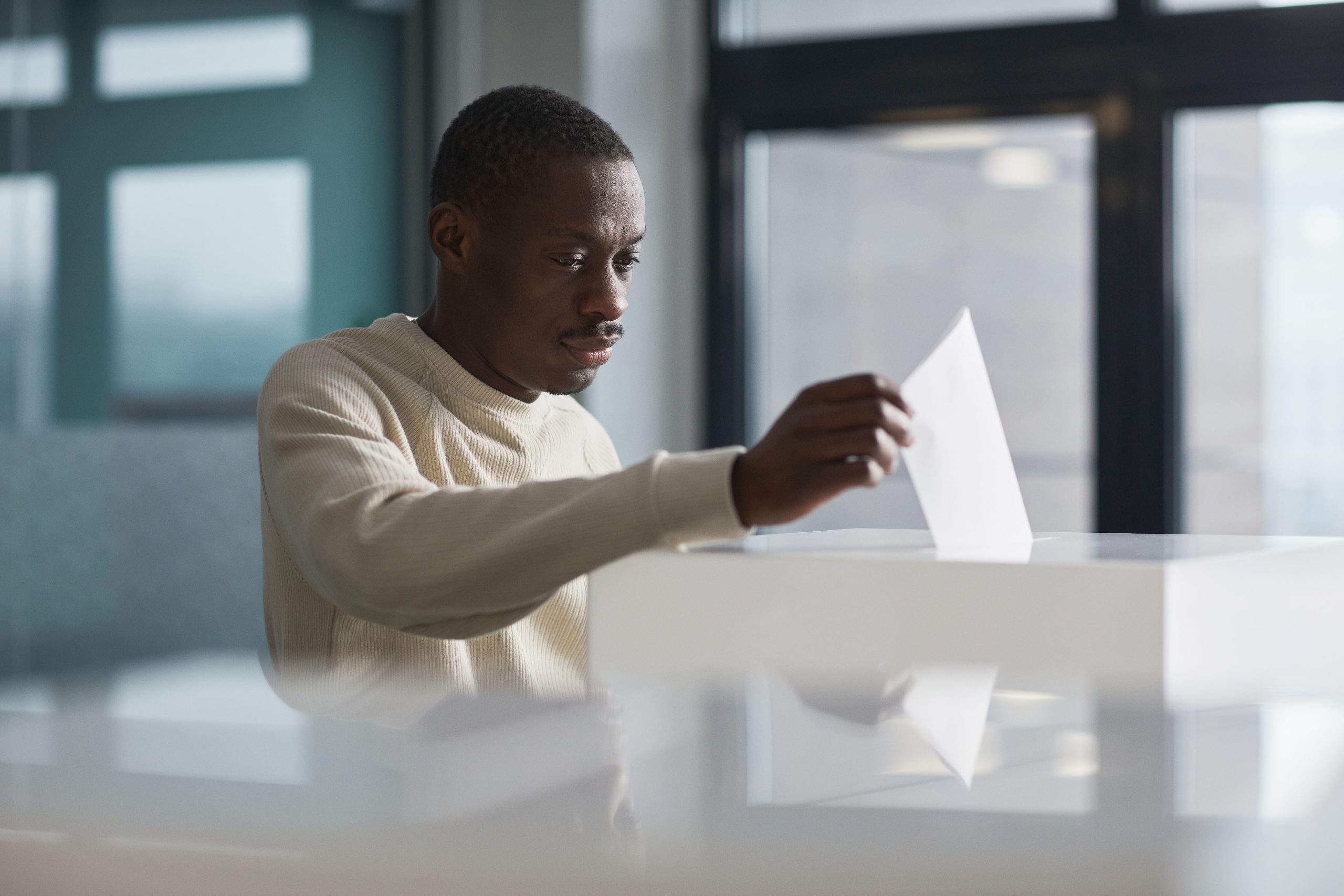 A young man casting his ballot at an indoor polling station, illustrating voting behavior on election day.